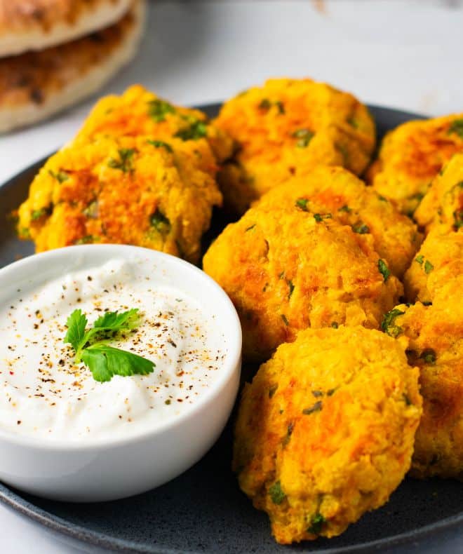 Baked Lentil Veggie Patties on a gray plate with yogurt sauce