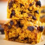 Close-up of stacked pumpkin oat muffins with chocolate chips, showing a moist, golden crumb on parchment paper.”
