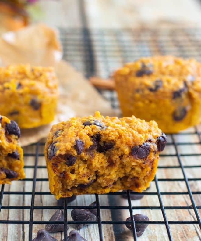 Pumpkin oat muffins with chocolate chips cooling on a wire rack, with a soft, golden texture and scattered chocolate chips visible.