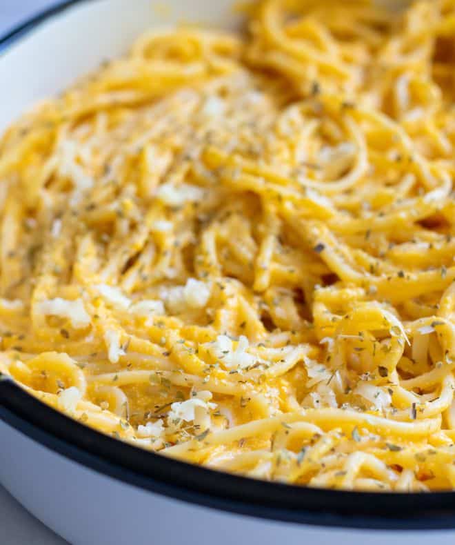 Plate of light creamy high-protein pasta with a rich cheesy sauce, topped with herbs and shredded cheese