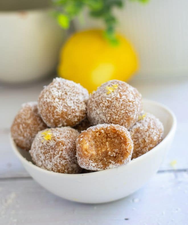 Healthy Lemon Energy Balls in a white bowl and a lemon in the background