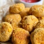 Crispy baked tofu nuggets on brown paper with a bowl of ketchup