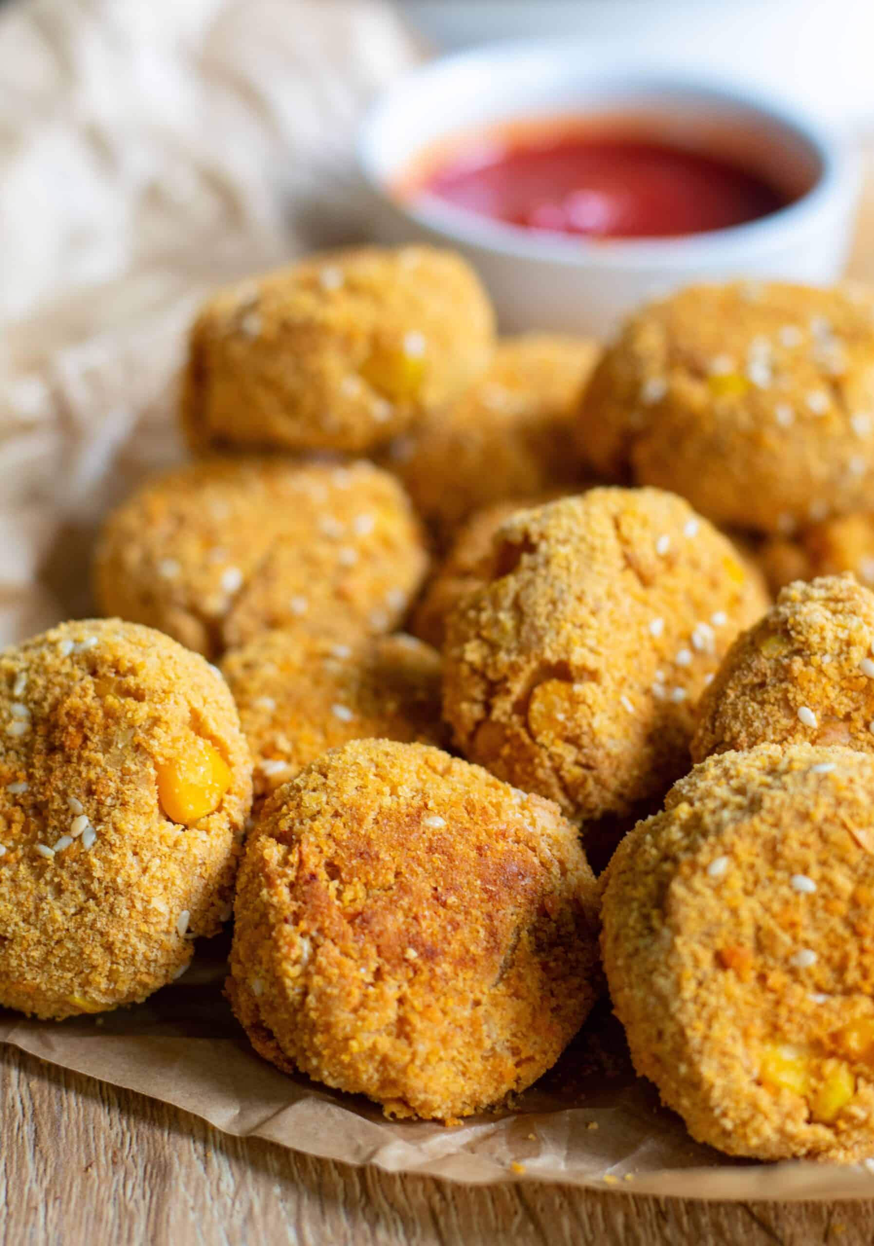 Crispy baked tofu nuggets on brown paper with a bowl of ketchup