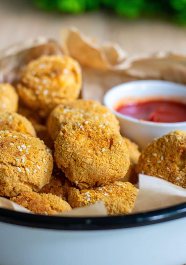 Crispy Tofu Baked Nuggets on a brown paper with a bowl of ketchup on the side