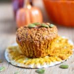 Healthy Pumpkin Protein Muffin on a white liner with pumpkin seeds around