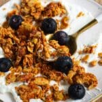 Peanut Butter Protein Granola Clusters on a plate with yogurt and blueberries