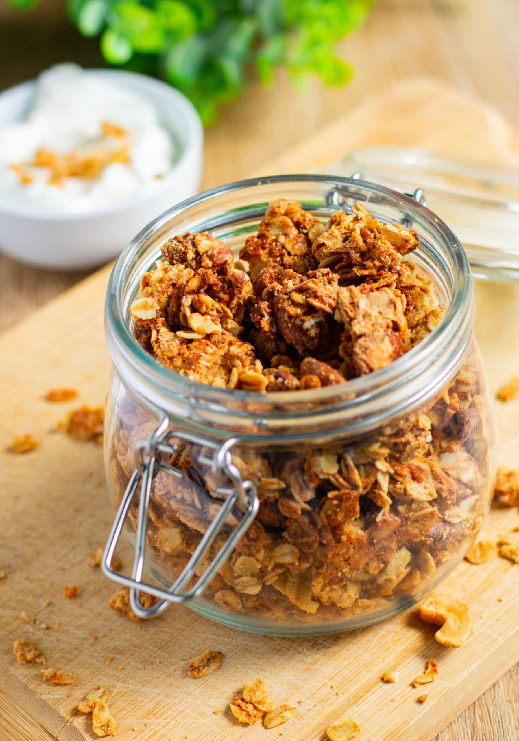 Peanut Butter Protein Granola Clusters in a small jar on a wooden board