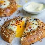 A bagel cut in the middle with a runny egg inside